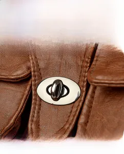 Close-up of silver oval twist lock on brown lychee texture leather shoulder bag