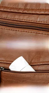 Detail of brown textured leather baguette bag with metal zipper and rear pocket