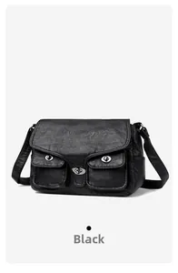 Detail view of black textured leather baguette bag with dual metallic buckle pockets