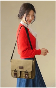 Detail of khaki canvas crossbody bag with brown leather trim and twin front pockets