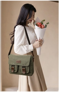 Close-up of green canvas messenger bag featuring leather straps and front pockets details
