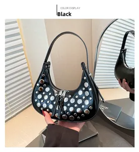Detail of black crescent hobo bag with silver metallic rivets and sleek zipper closure