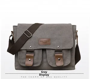 Front detail of gray canvas messenger bag with leather labels and silver rivet pockets