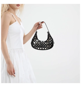 Detail of black semi-moon handbag with silver studs and polished leather texture