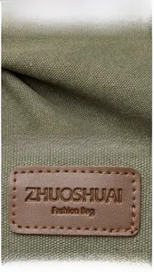 Detail of green canvas texture with leather brand logo and front zipper pocket