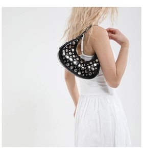 Close-up of black crescent shoulder bag with silver metal rivets and punk style details