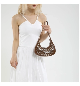 Detail showing brown leather hobo bag with silver rivet studs on a white outfit model