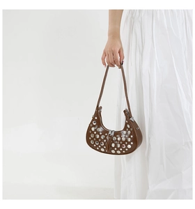 Detail of dark brown leather bucket bag with silver studs and leather tassels