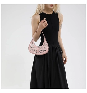 Close-up of pink hobo bag with silver eyelets and rivets on shiny patent leather