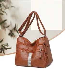 Detail of a brown vintage leather bag showing three zipper pockets and rhinestone accents