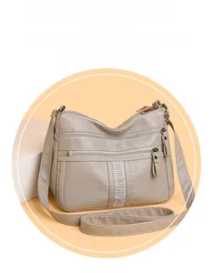 Detail of grey faux leather crossbody bag with multiple zippers and rhinestone stripe