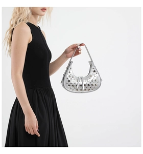 Detail of silver metallic eyelet handbag with punk style rivets on crescent hobo bag