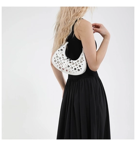 White crescent underarm bag with silver metal grommet studs and adjustable shoulder strap