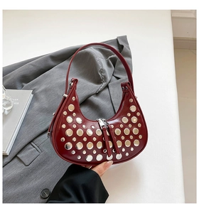 Macro shot of silver studs and dual zippers on burgundy leather crescent shoulder bag