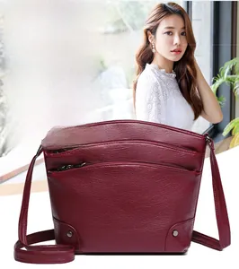 Detail of burgundy bucket bag featuring multi-layer zippers and lychee grain texture