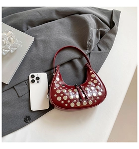 Detail of burgundy leather crescent bag with silver rivet studs and industrial chic style