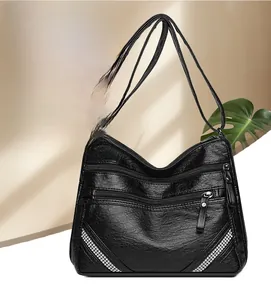 Dettaglio della borsa a tracolla in pelle martellata nera con cerniere e decori in strass