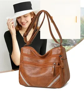 Dettaglio di una grande borsa a tracolla marrone con tasche multiple e decorazioni strass