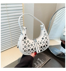 Detailed close-up of white crescent hobo bag featuring silver rivets and top double zip closure