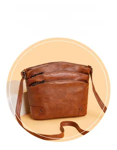 Close-up of brown PU leather bucket bag with three separate zipper layers and metal rivets