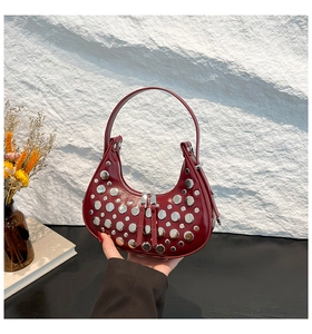 Close-up of deep wine red crescent shoulder bag with silver studs and metal zippers