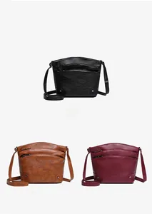 Detailed view of multi-layered faux leather crossbody bags in black, brown, and red colors