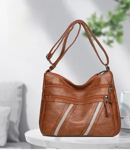Detail view of brown pebbled leather bag with multiple zippers and rhinestone accents