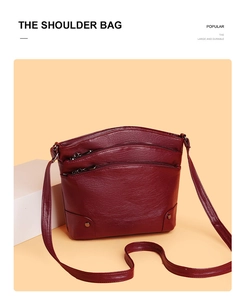 Close-up of wine red leather shoulder bag with triple zipper layers and metal rivets