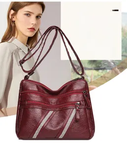 Macro detail of wine red pebbled leather shoulder bag with rhinestone zippers and compartments