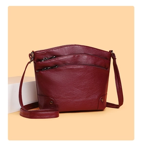 Detailed view of burgundy multi-layer crossbody bucket bag with zippers and metal studs