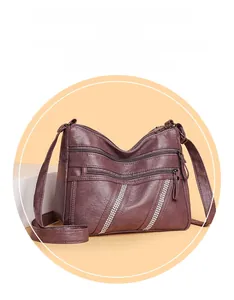 Detail of burgundy PU leather crossbody bag with multiple zippers and diamond accents