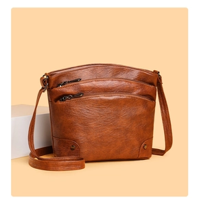 Detail view of vintage brown crossbody bucket bag featuring multiple zipper compartments