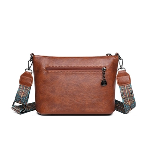 Vintage braune Bucket Bag aus Leder mit buntem Ethno-Schultergurt auf weißem Hintergrund