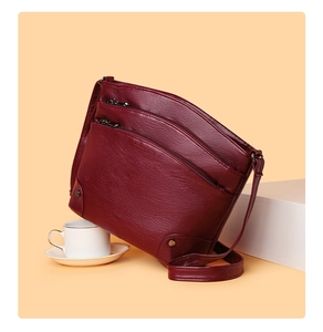 Close-up of wine red multi-zipper leather bucket bag with three compartments and metal rivets
