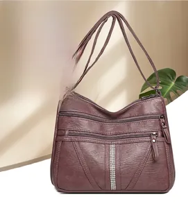 Close-up of vintage burgundy crossbody bag featuring multi-pocket zippers and rhinestone trim