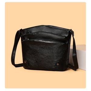 Detail of black multi-zipper bucket bag with pebbled leather texture and metal studs