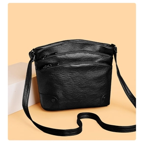 Close-up of black leather bucket bag featuring functional zippers and lychee texture