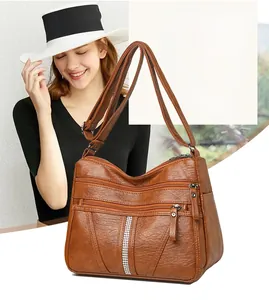 Detailed view of the brown soft leather crossbody bag with triple zippers and rhinestone trim