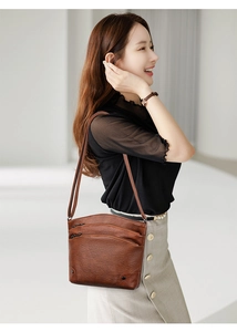 Detail of a brown multi-layer bucket bag with three zipper pockets and black rivets