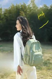 Gros plan d'un sac à dos léger en nylon vert avec plusieurs compartiments zippés pour voyage