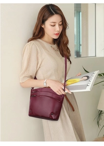 Detail of burgundy bucket bag with multi-layer zippers and lychee grain leather finish