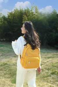 Détail d'un sac à dos léger en nylon jaune vif avec plusieurs poches sur un mannequin femme