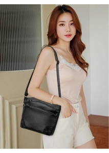 Detail of black lychee grain leather bucket bag featuring multi-layer zipper compartments