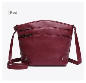 Detail shot of vintage dark red bucket bag showing layered zippers and litchi grain texture