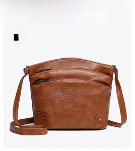 Front view of brown bucket bag showing multi-zipper compartments and metallic rivets