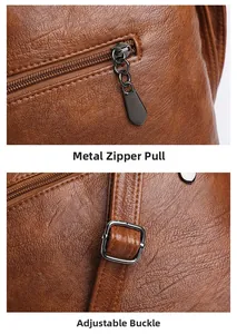 Detail of dark grey zipper pull and adjustable strap buckle on brown leather bag