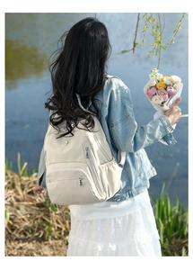 Détail d'un sac à dos en nylon imperméable blanc cassé avec plusieurs poches en extérieur