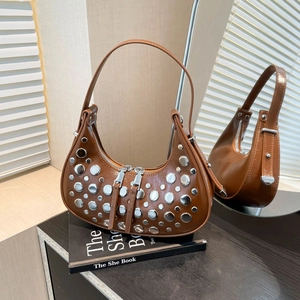 Brown leather underarm bag with silver rivets and double zipper on a mirrored surface