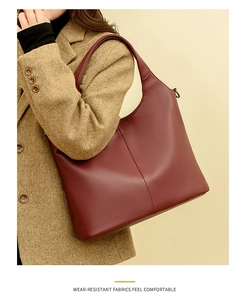 Detail of burgundy lychee leather tote bag with stitch seam on brown winter coat