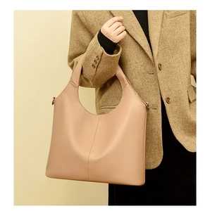 Detail of beige textured leather tote bag with vertical stitching and metal side hooks